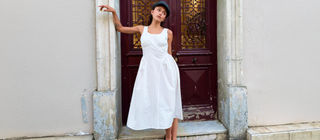 women wearing a white dress against a door outside. 