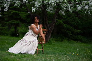 Women wearing a white dress sitting in a garden under a cherry blossom.