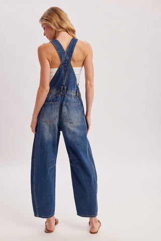 Person wearing a denim jumpsuit on a white background