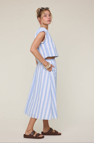 Woman wearing a light blue and white striped outfit on a beige background