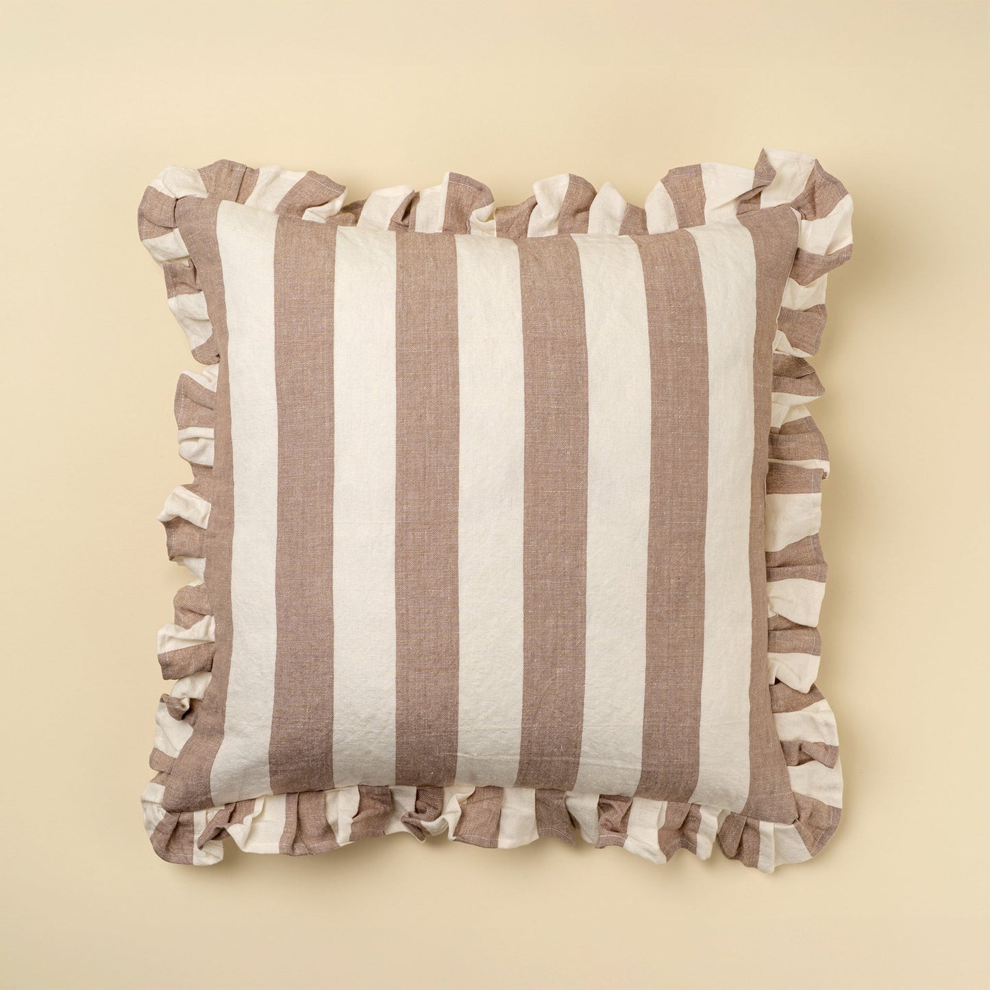 Striped pillow with ruffled edges on a beige background