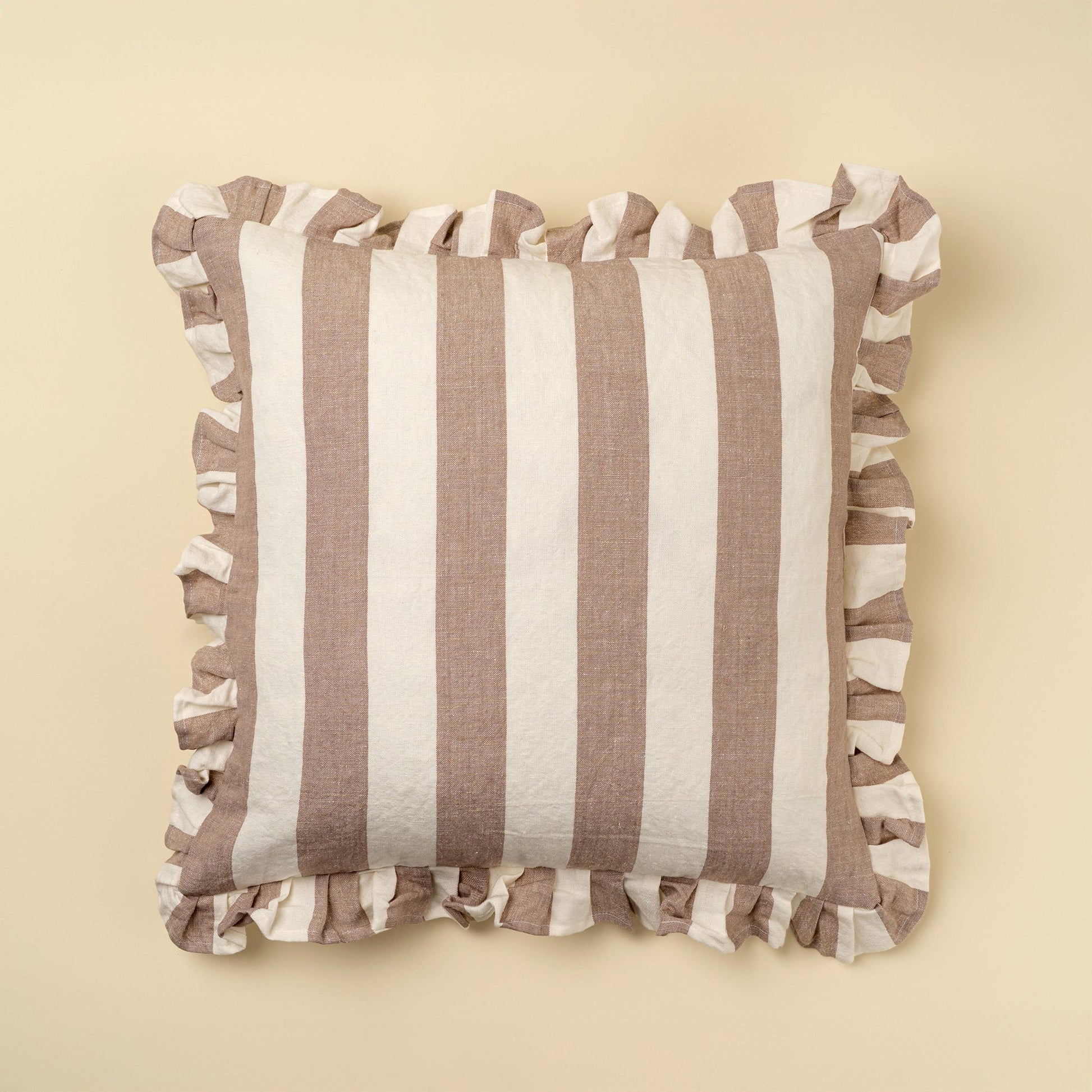 Striped pillow with ruffled edges on a beige background