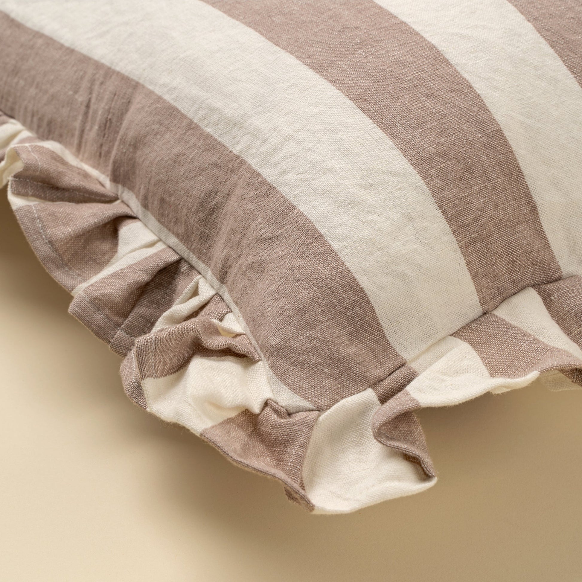 Striped pillow with ruffled edge on a beige background