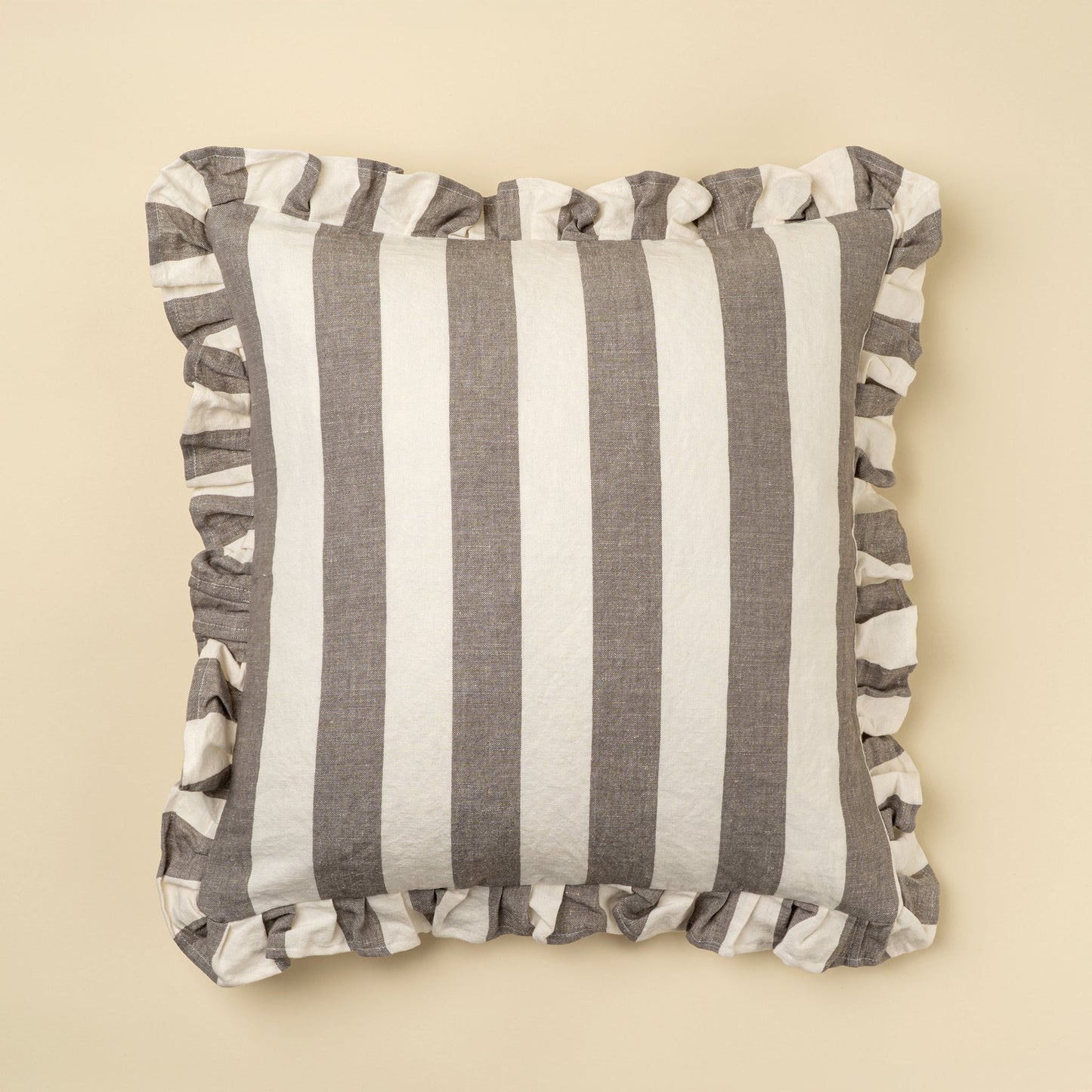 Striped pillow with ruffle trim on a beige background