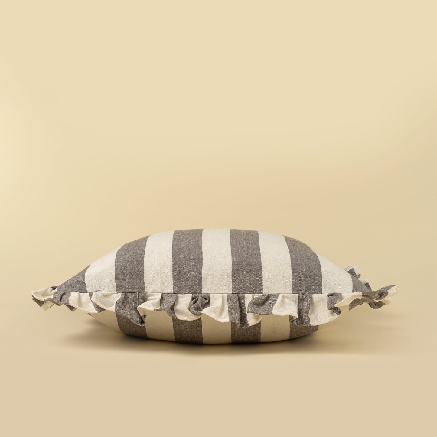 Striped pillow with ruffle trim on a beige background