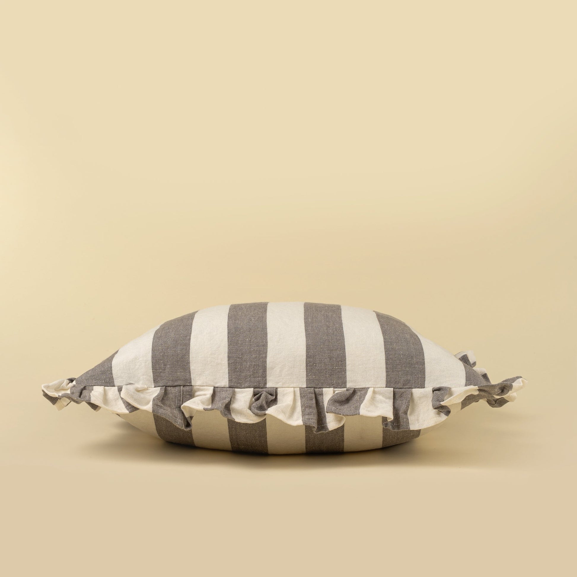 Striped pillow with ruffle trim on a beige background