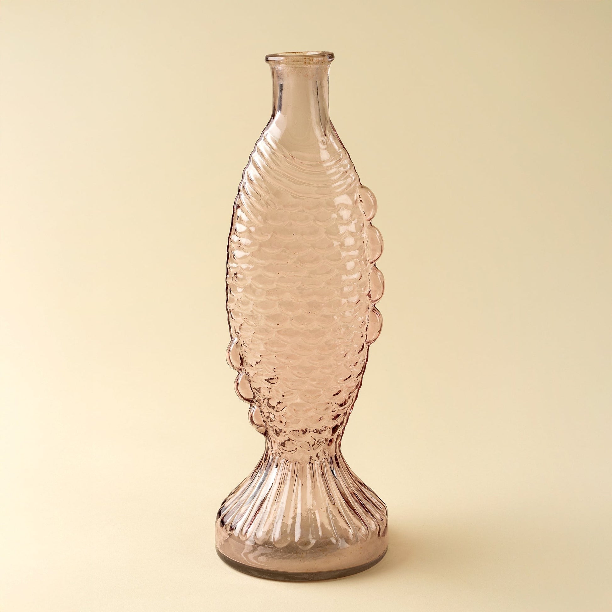 Pink fish glass vase with textured design on a beige background