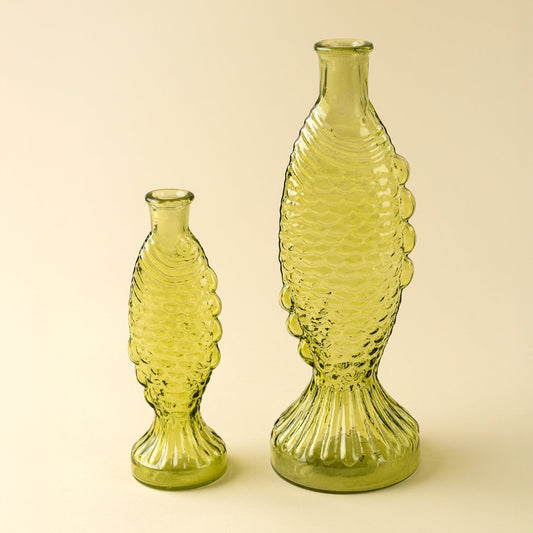 Two green fish glass vases with textured design on a beige background
