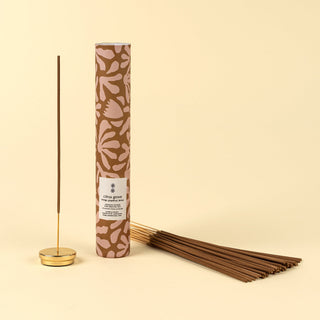 Incense stick with patterned cylindrical packaging on a beige background