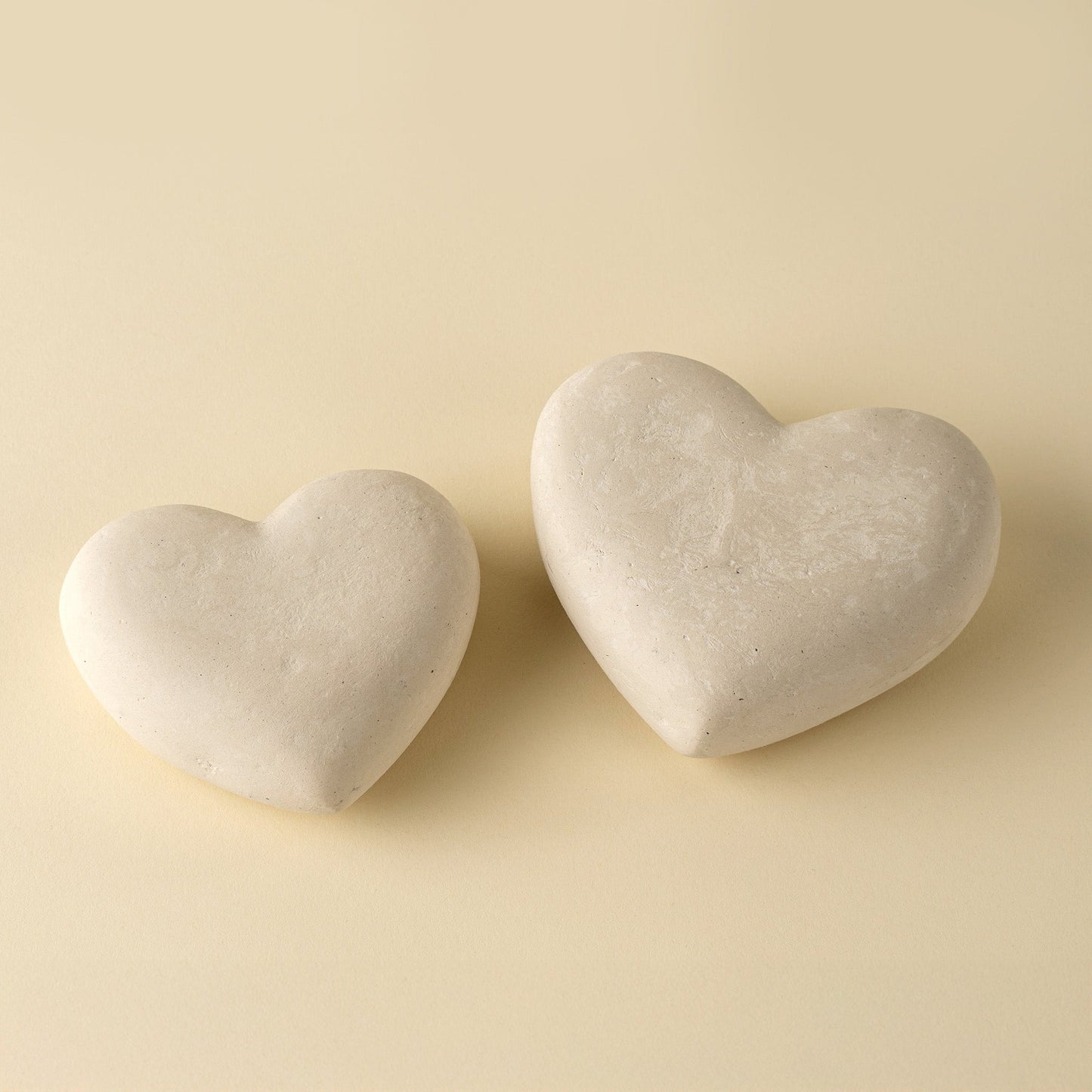Two heart-shaped stones on a beige background