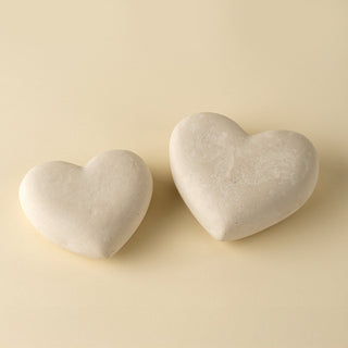 Two heart-shaped stones on a beige background