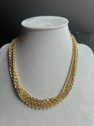 Gold necklace on a gray mannequin bust against a dark background