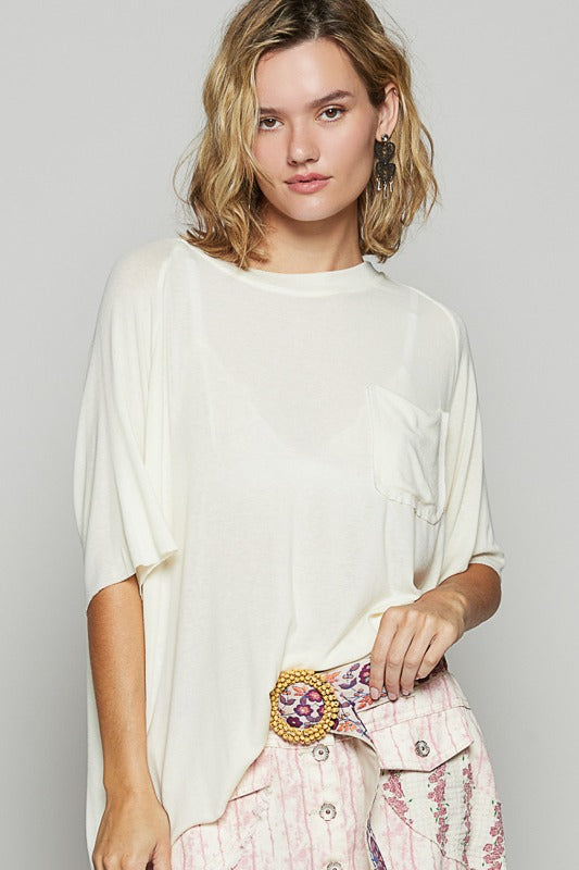 Woman wearing a white oversized shirt with a decorative belt and pink pants on a plain background