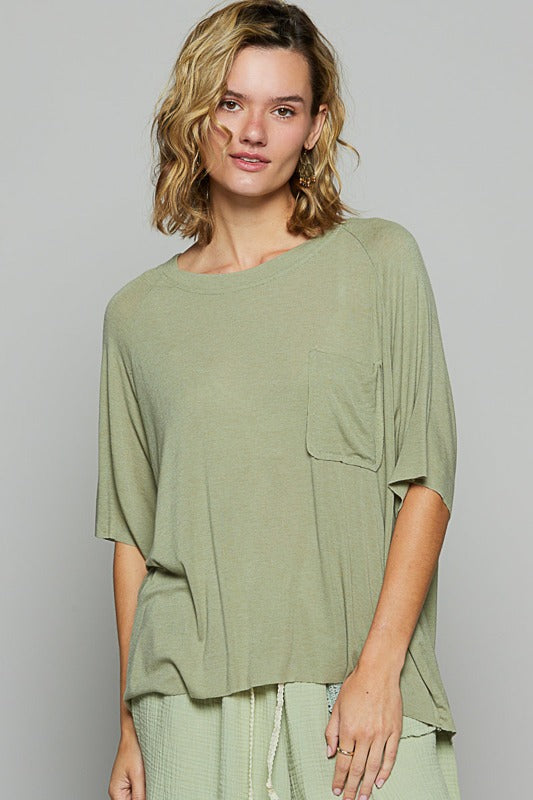 Woman wearing a green oversized top against a gray background