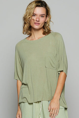 Woman wearing a green oversized top against a gray background