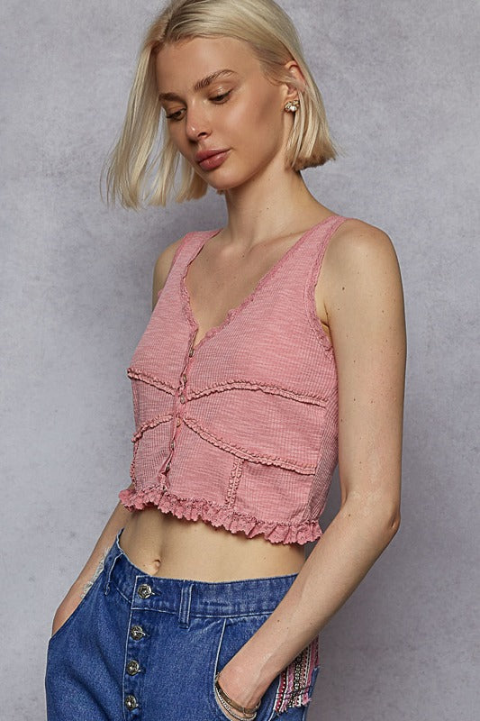Woman wearing a pink crop top and blue jeans against a gray background