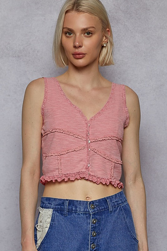 Woman wearing a pink textured top and blue denim skirt against a gray background