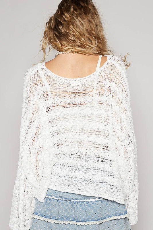 Woman wearing a white lace top and denim shorts on a plain background
