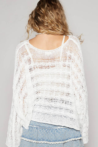 Woman wearing a white lace top and denim shorts on a plain background
