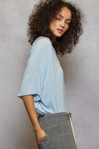 Person wearing a light blue shirt and striped pants against a plain background