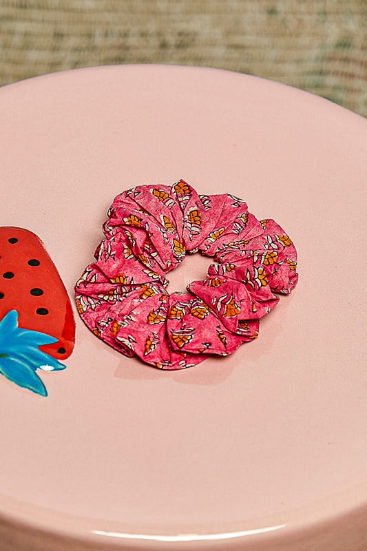 Pink scrunchie with butterfly pattern on a pink surface