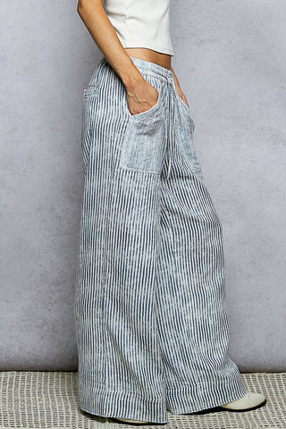 Person wearing blue and white striped wide-leg pants against a gray background
