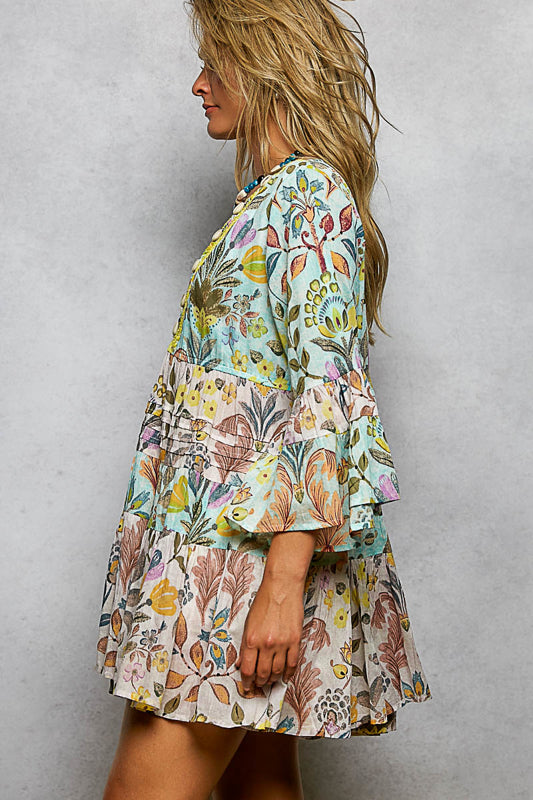Woman wearing a colorful floral dress against a plain background