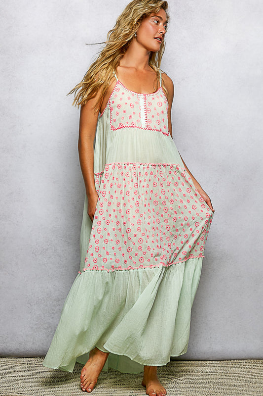 Woman wearing a light green dress with pink floral patterns against a plain background