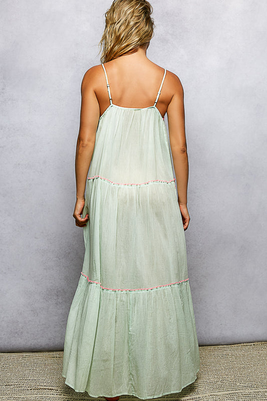 Woman wearing a light green dress with thin straps against a plain background