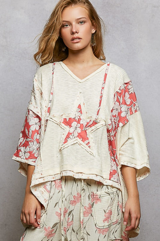 Woman wearing a floral kimono-style top and pants against a gray background