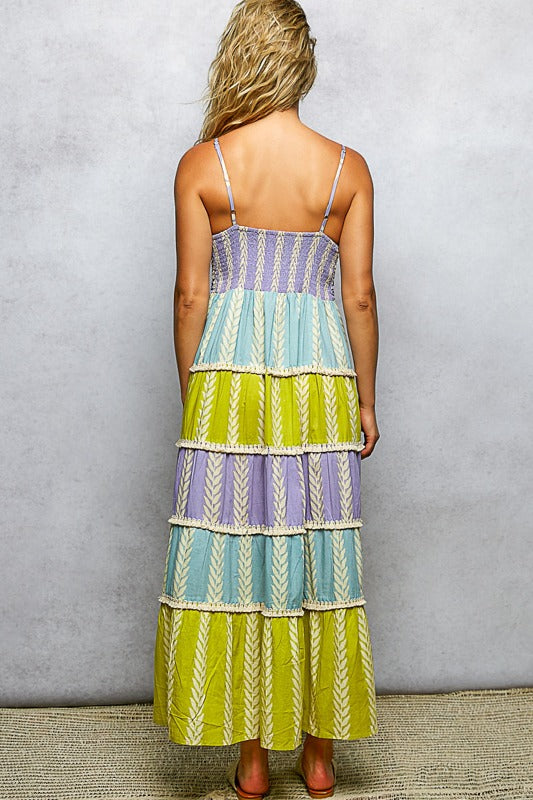 Woman wearing a colorful tiered dress against a plain background