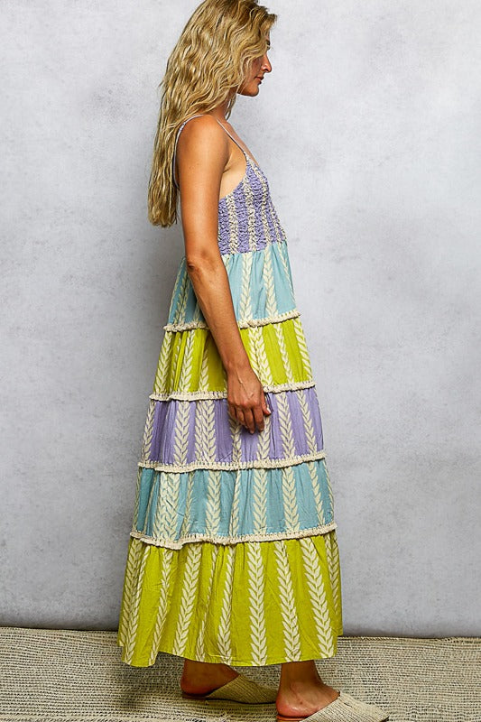 Woman wearing a colorful tiered dress against a plain background