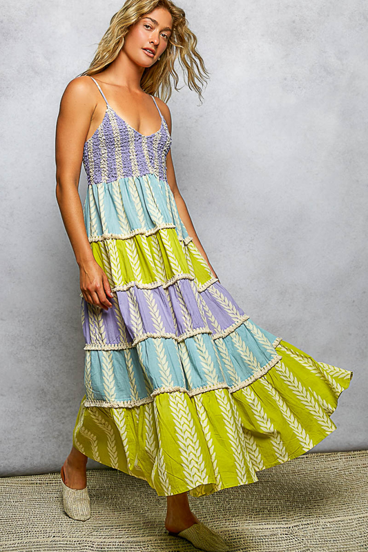 Woman wearing a colorful tiered dress against a gray background