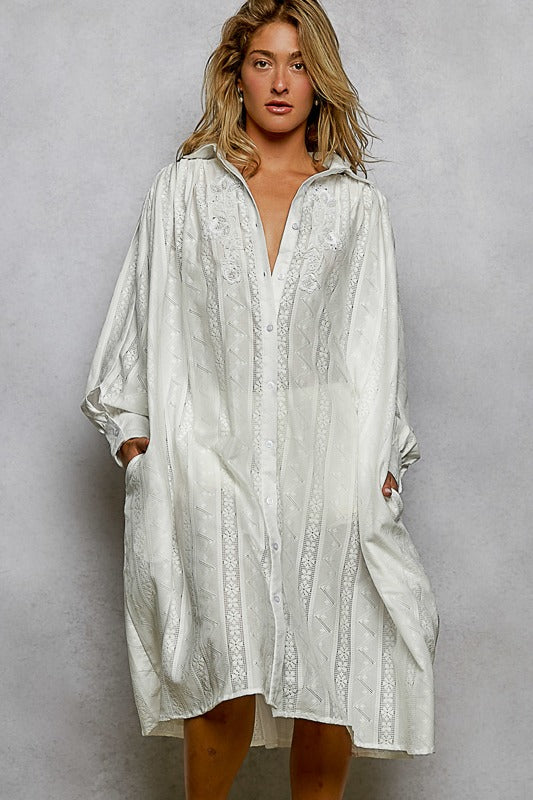 Woman wearing a white patterned dress against a gray background