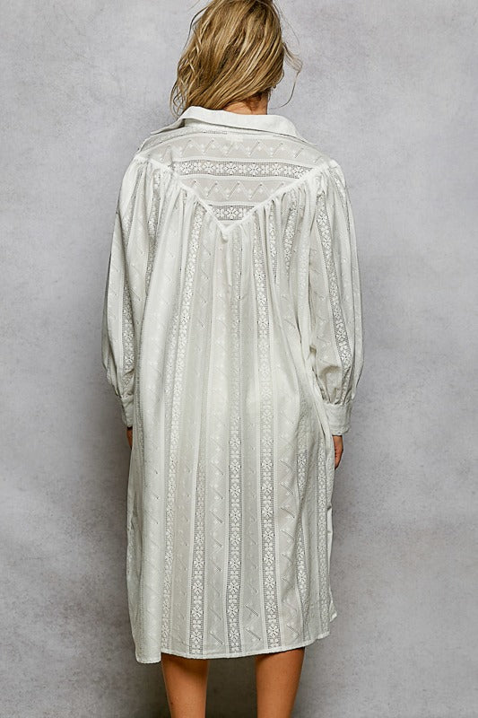 Light-colored lace dress worn by a person against a gray background