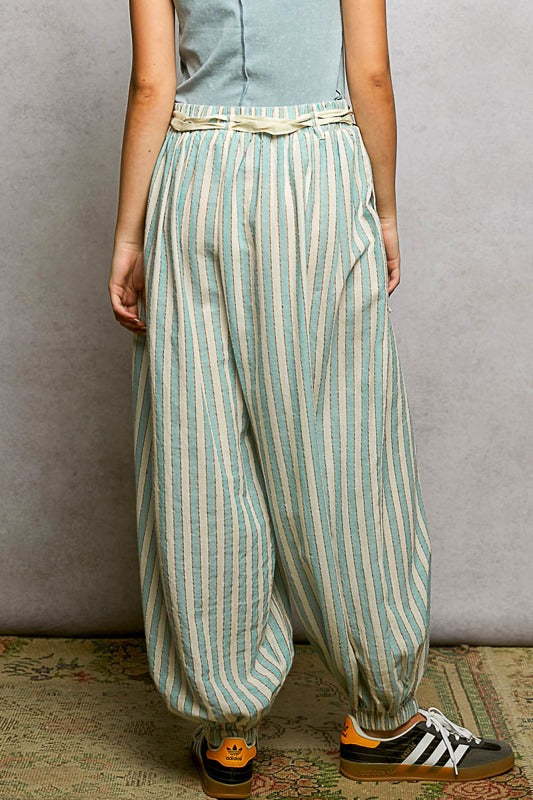 Person wearing light blue and white striped pants with a plain background