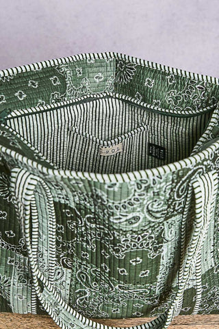 Green patterned fabric bag with visible brand label on a light gray background