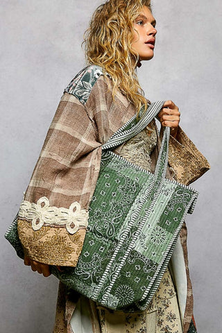 Person holding a green patterned bag with a textured brown bag over their shoulder against a gray background