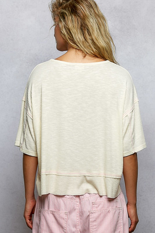 Person wearing a beige top and pink pants against a plain background