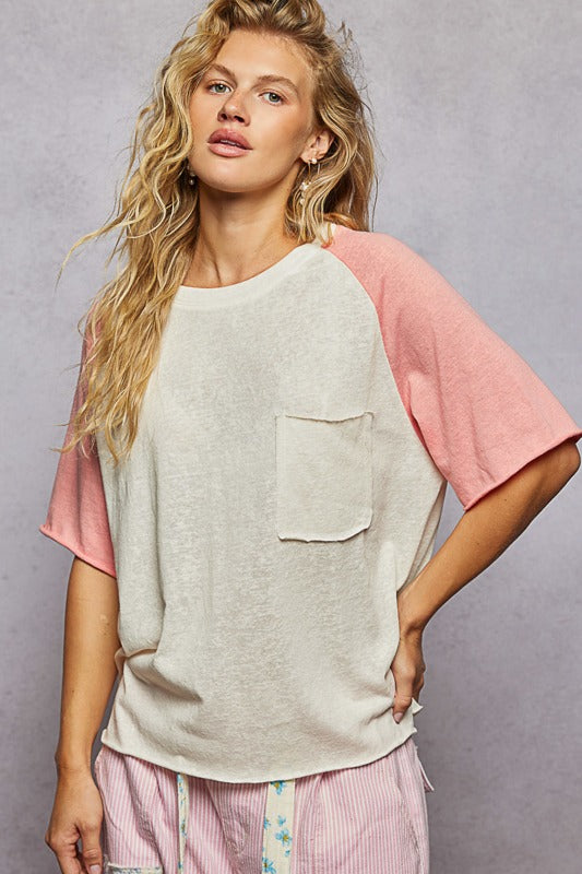 Woman wearing a light gray and pink top with a plain background