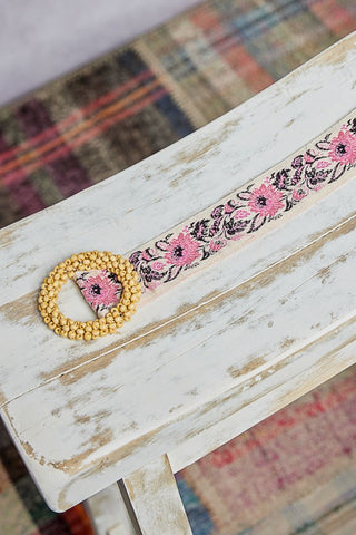Decorative belt with floral pattern on a wooden surface