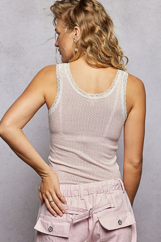 Woman wearing a light pink sleeveless top and pants against a gray background
