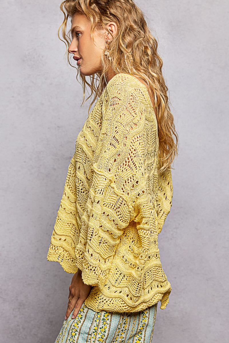 Woman wearing a yellow crochet sweater against a gray background