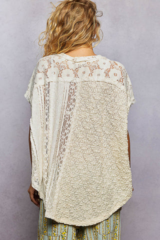 Back view of a person wearing a lace-trimmed top against a plain background
