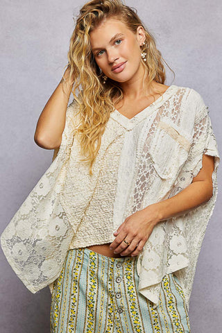 Woman wearing a lace top and patterned pants against a gray background