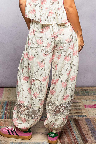 Person wearing floral pants and colorful shoes on a patterned rug.