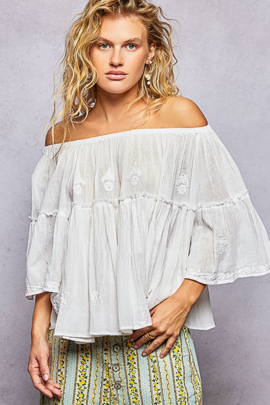 Woman wearing a white off-shoulder top with a gray background