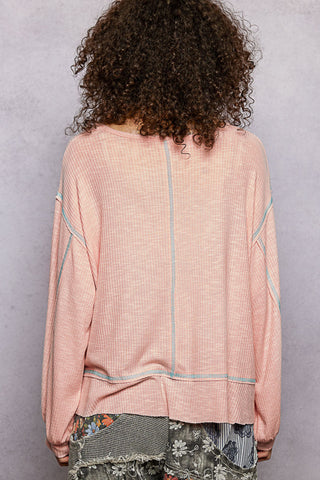 Person wearing a pink textured top with a gray background