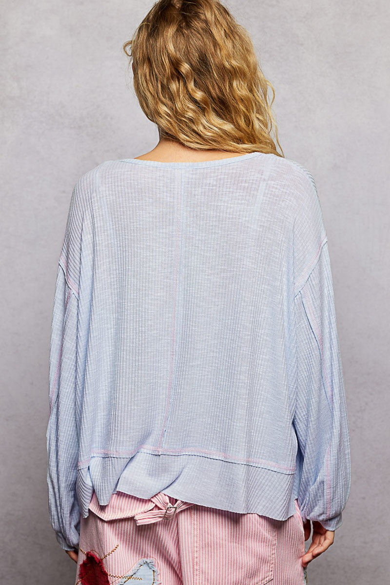 Person wearing a light blue oversized sweater with pink pants against a gray background