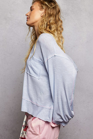 Woman wearing a light blue ribbed sweater against a gray background
